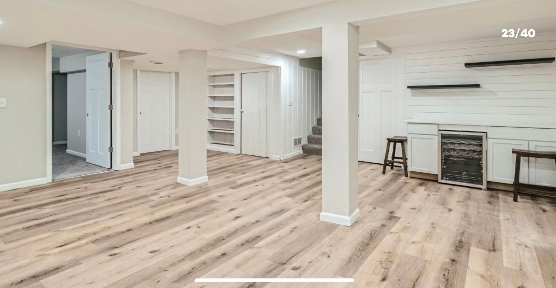 An empty basement with hardwood floors and white walls.