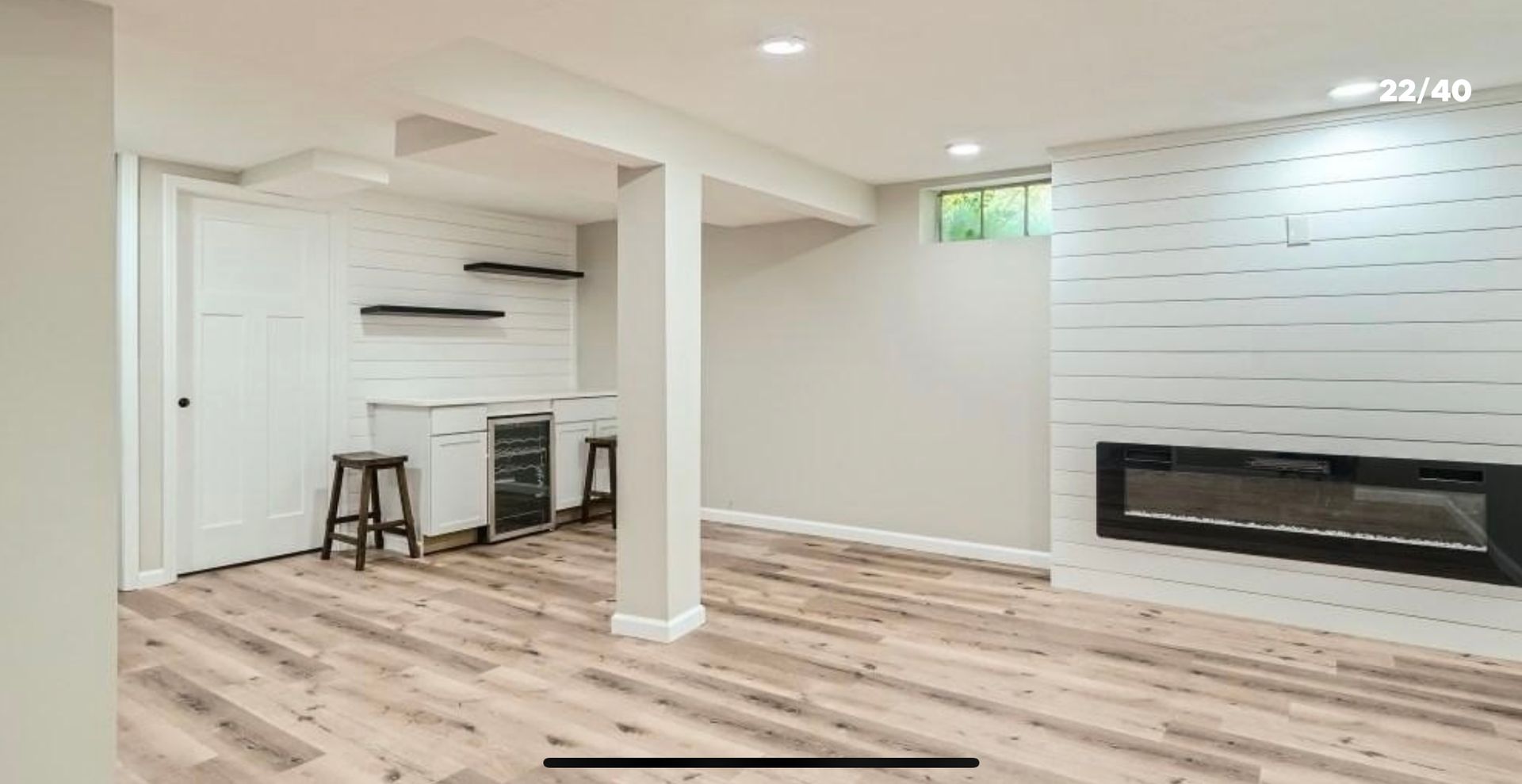 An empty basement with hardwood floors and a fireplace.