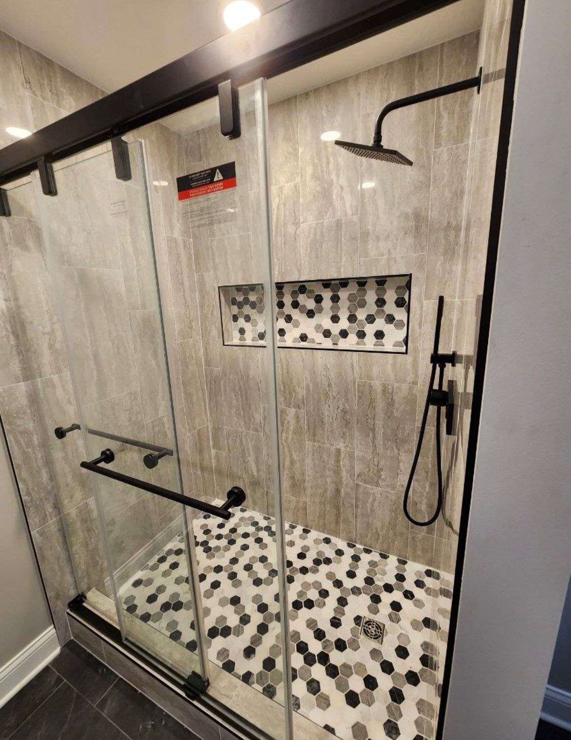 A bathroom with a sliding glass shower door and a shower head.