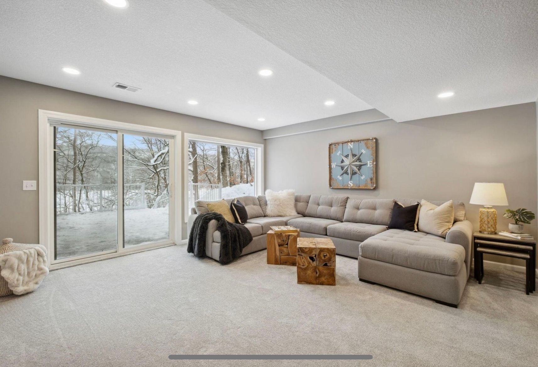 A living room with a large sectional couch and sliding glass doors.