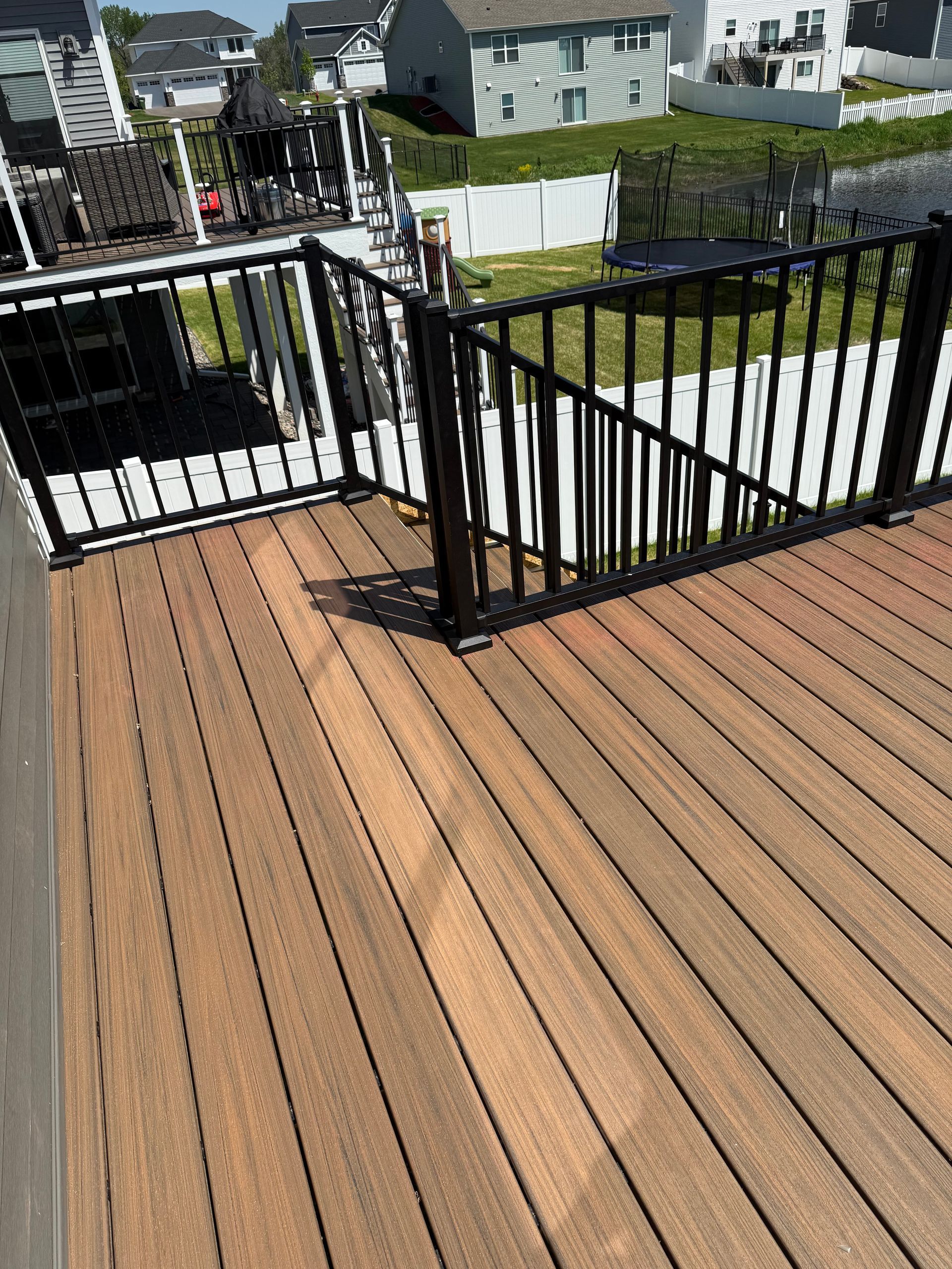 A wooden deck with a black railing and stairs leading up to it.