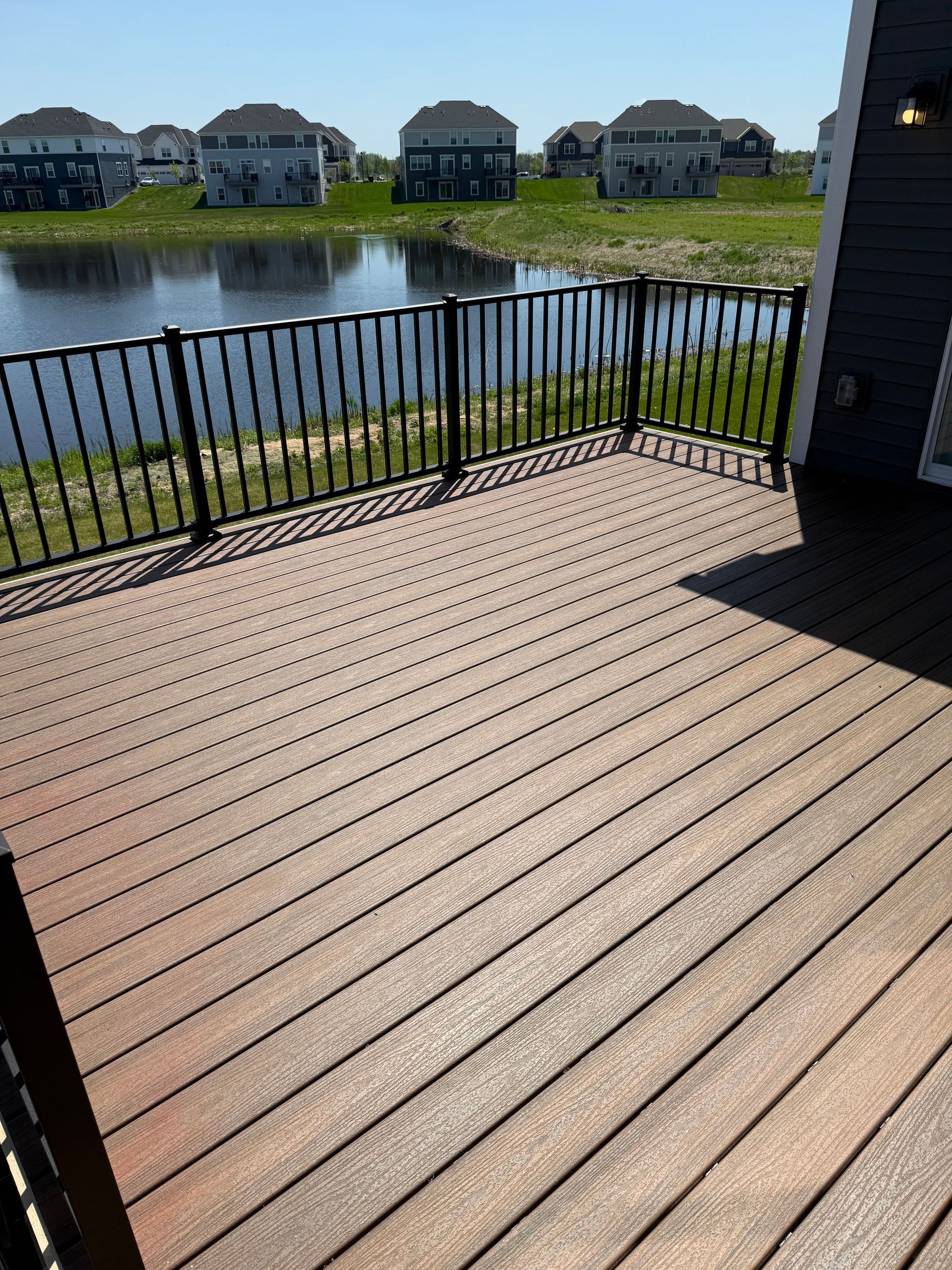A wooden deck with a metal railing overlooking a body of water.