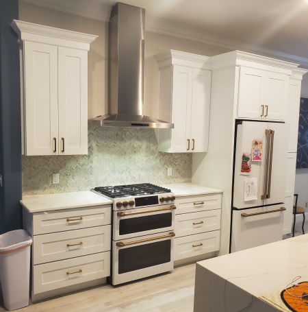 White kitchen with stainless steel range hood and appliances, white cabinets and countertops.