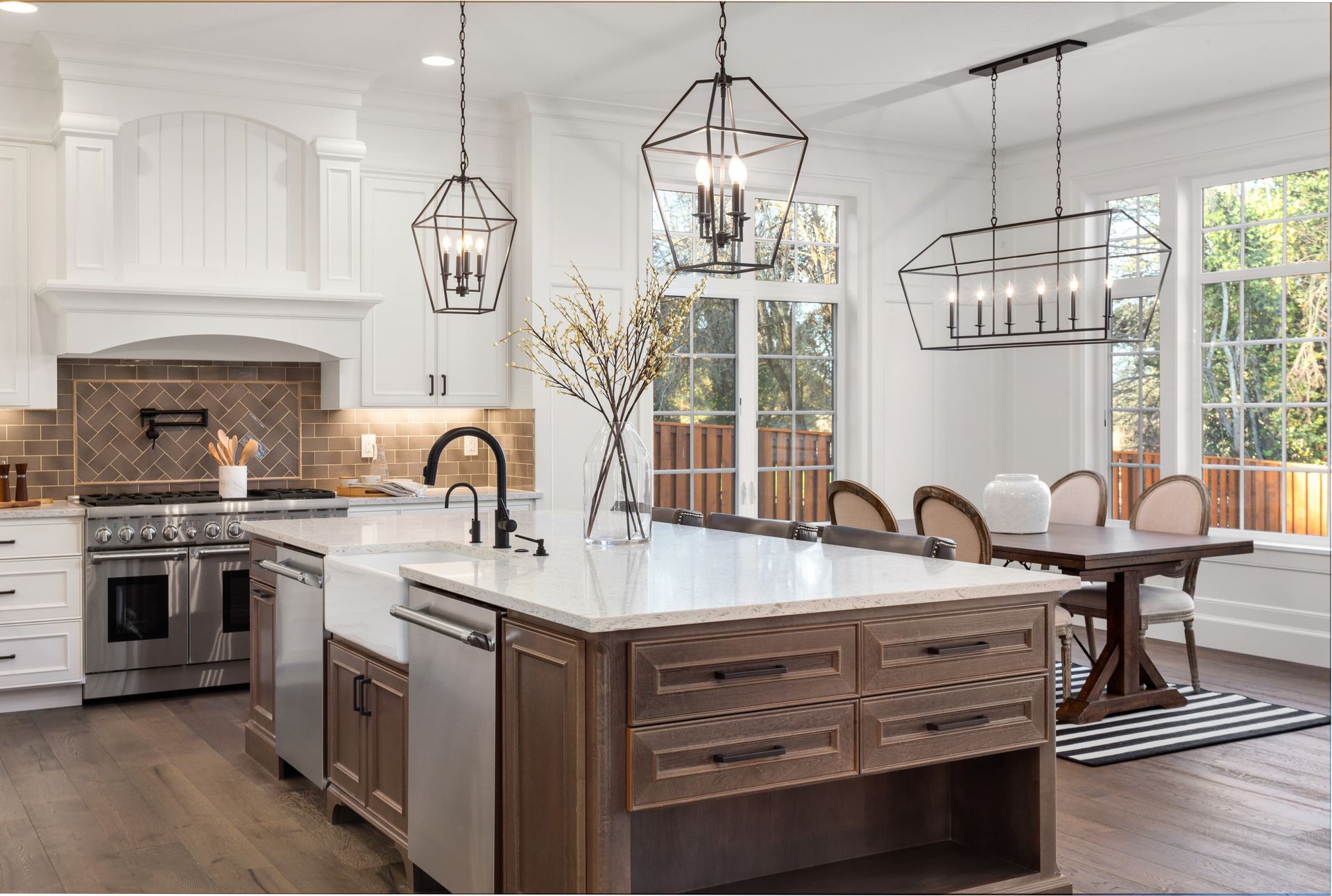 Elegant kitchen with island, pendant lights, wooden floor, and dining table.