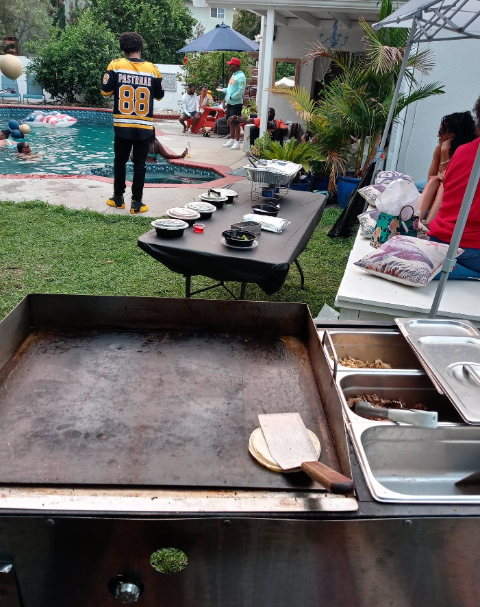 A flat grill with food items, people near a pool, and a person in a Steelers jersey.