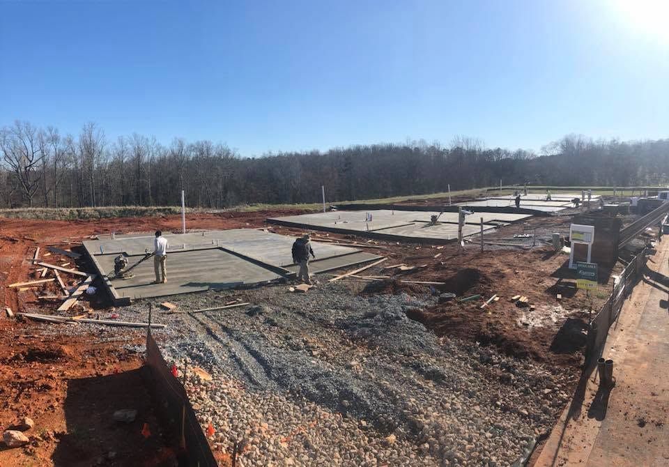 Construction site with workers laying a foundation on a gravel slab under a clear sky