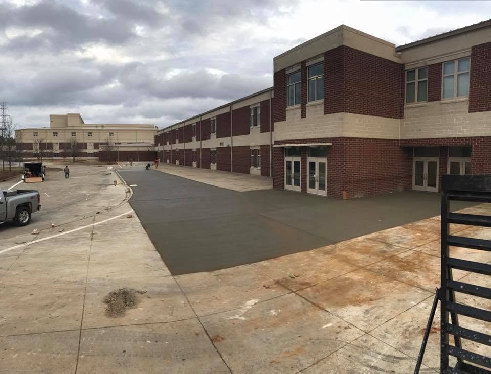 School building with freshly paved courtyard under cloudy sky