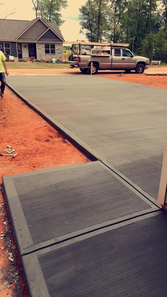 Accessible concrete ramp leading from a doorway to a driveway beside a house and parked truck.