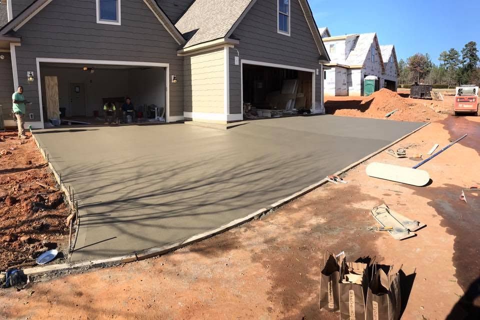 Fresh concrete driveway being poured at a new suburban home under construction