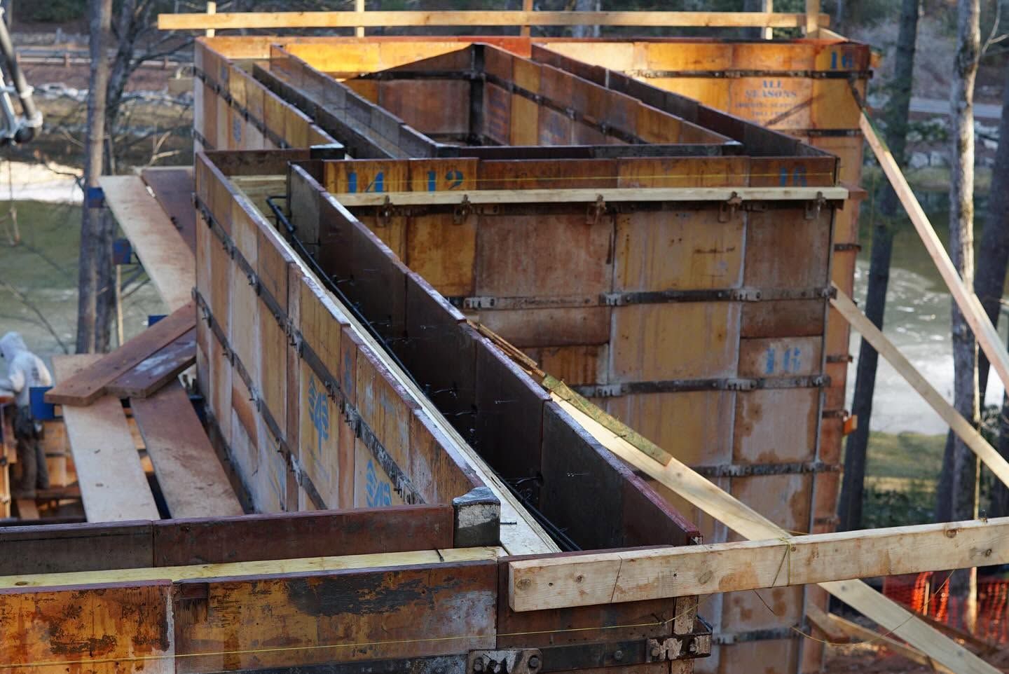 Rust-colored formwork for a concrete structure at a construction site, with wooden braces and metal supports.
