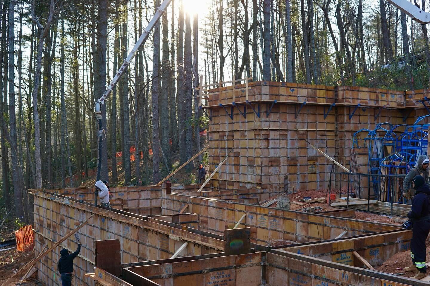 Construction site with wooden formwork and workers in a forest at sunset