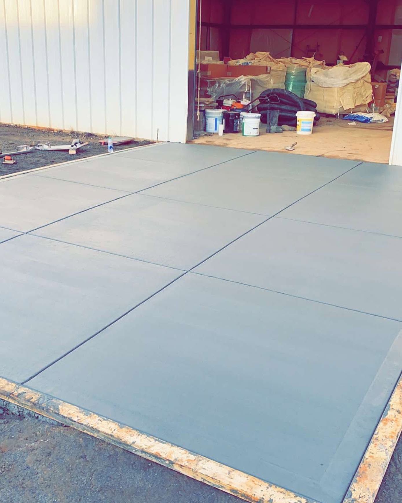 Blue concrete slabs laid in a garage opening beside storage boxes and buckets