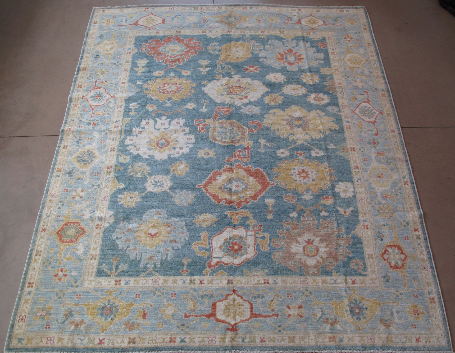 Blue and ivory floral patterned area rug with a cream-colored border and ornate detailing.