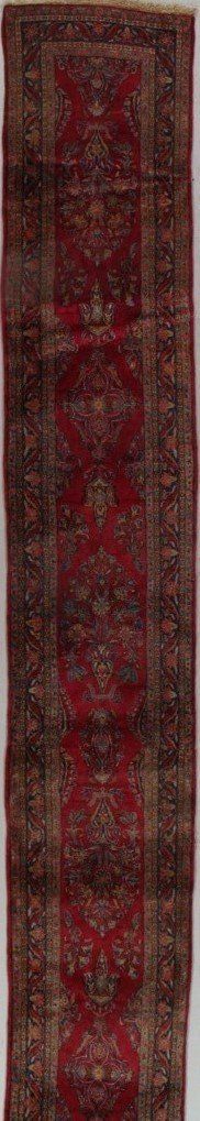 A close up of a red and brown rug on a white surface.
