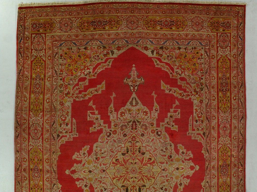 A red and gold rug with a castle on it is hanging on a wall.