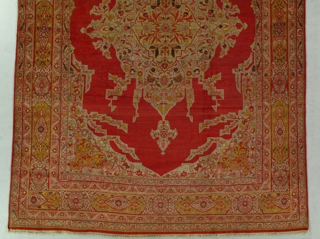 A red and gold rug with a castle on it is hanging on a wall.