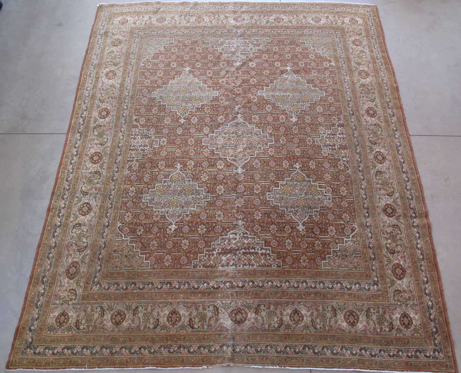 Large, rectangular Persian rug with a brown and cream color palette and ornate central pattern.