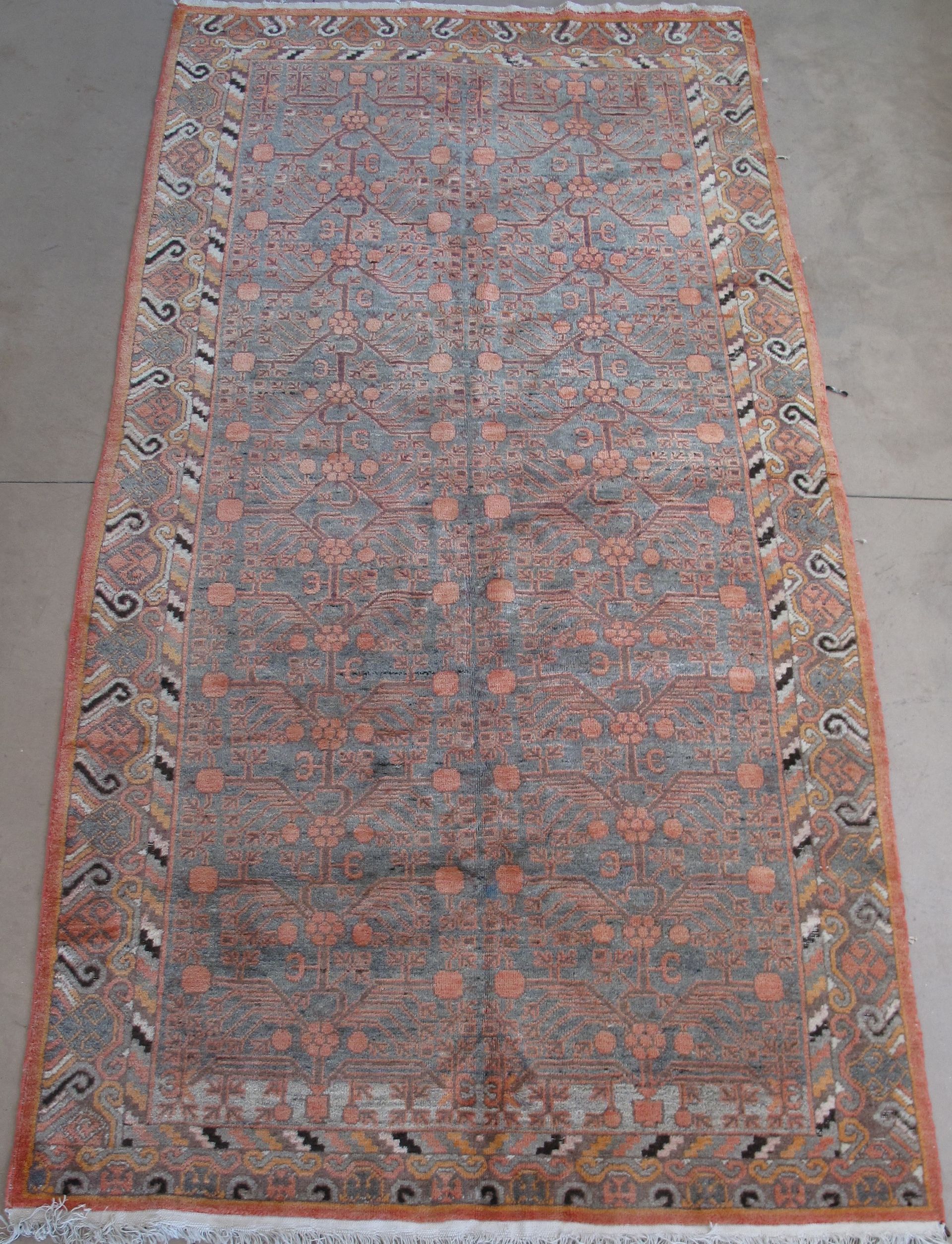 Rectangular brown oriental rug with patterned border and repeating floral motifs.
