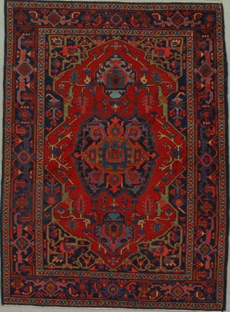 A red rug with a blue border is hanging on a wall