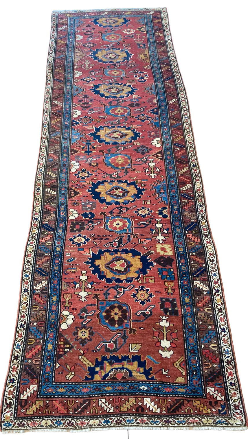 A long red and blue rug with a floral pattern on a white background.