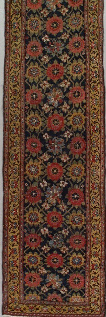 A rug with a floral pattern on it is hanging on a wall.