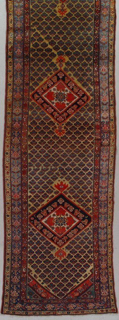 A long rug with a pattern on it is hanging on a wall.