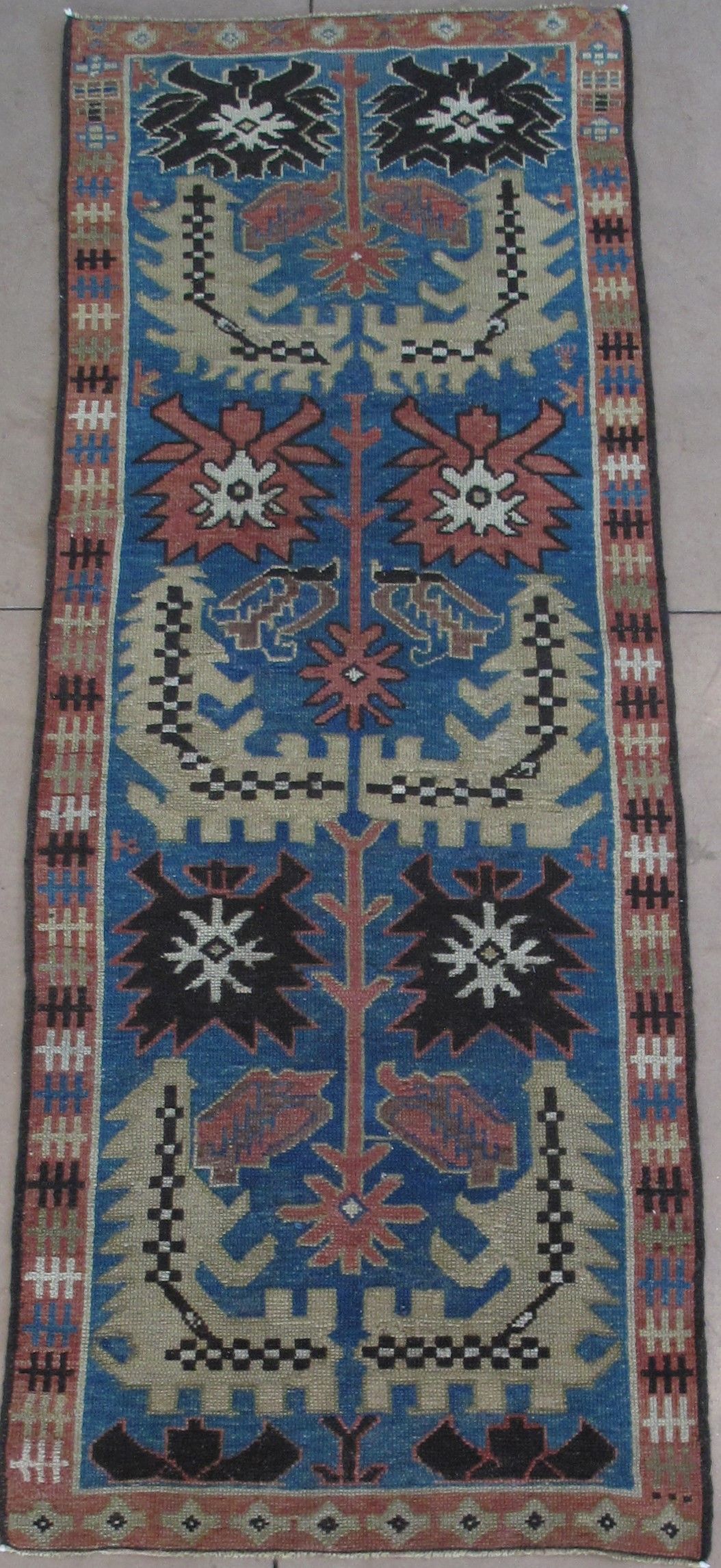 Blue, patterned rug with floral motifs and a brown border.