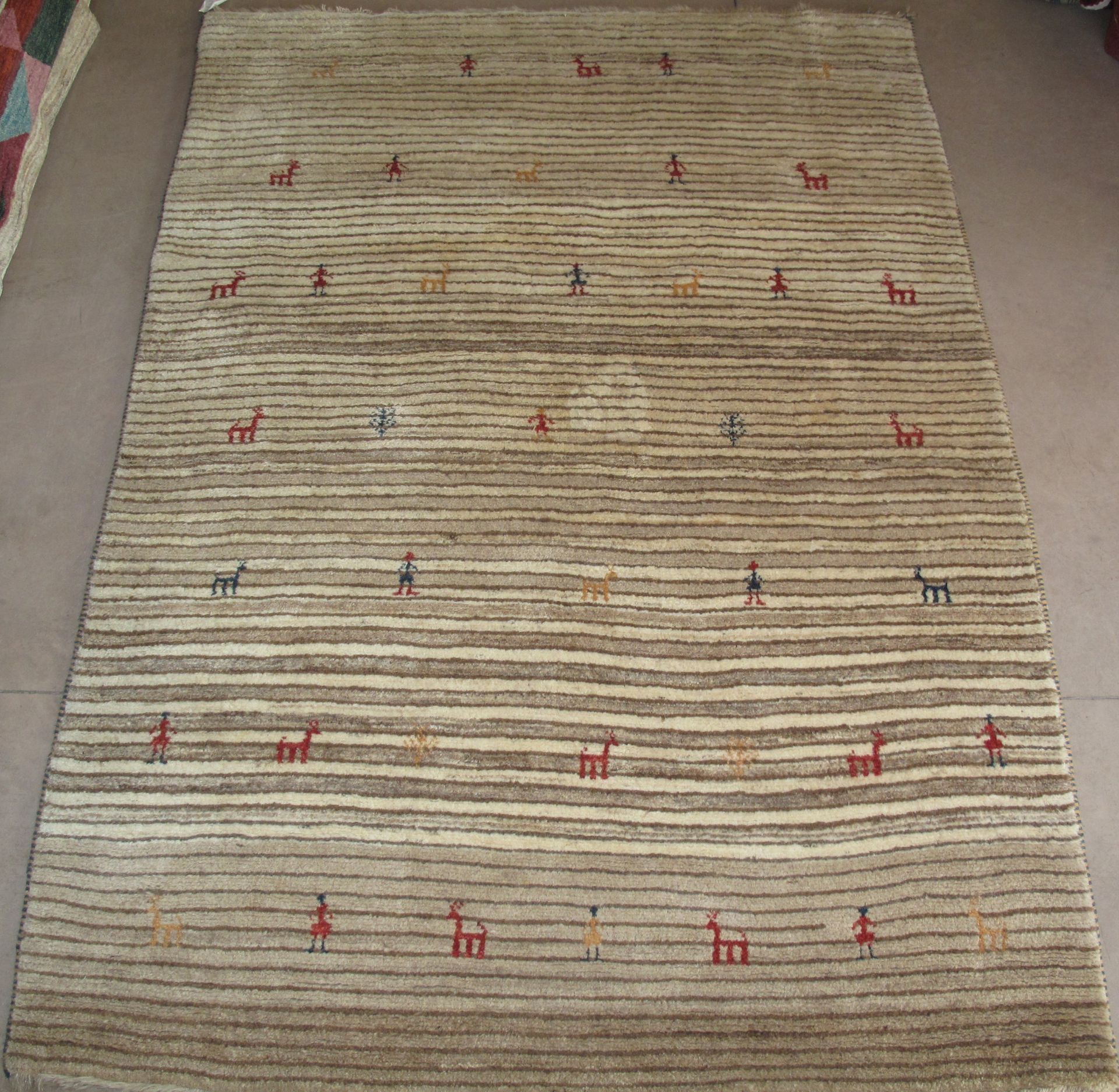 Tan and cream striped rug with small, colorful animal and person figures scattered across.