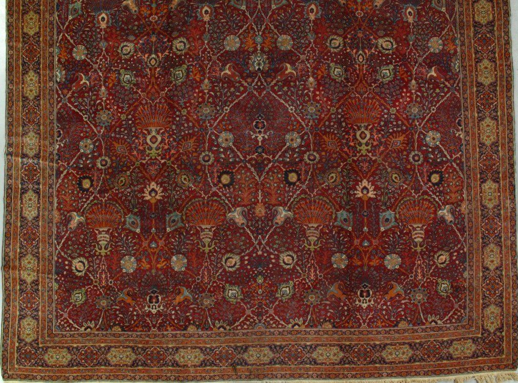 A red rug with a pattern on it is sitting on a white surface.