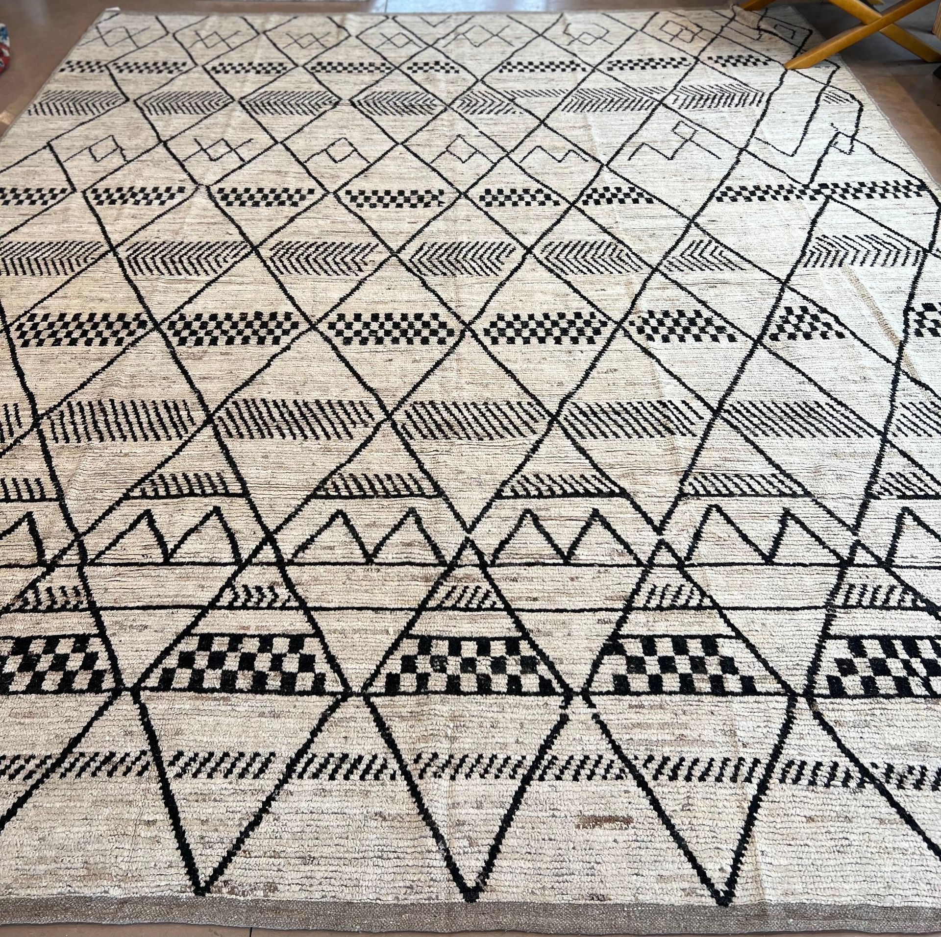 A rug with a black and white pattern on it is sitting on a wooden floor.