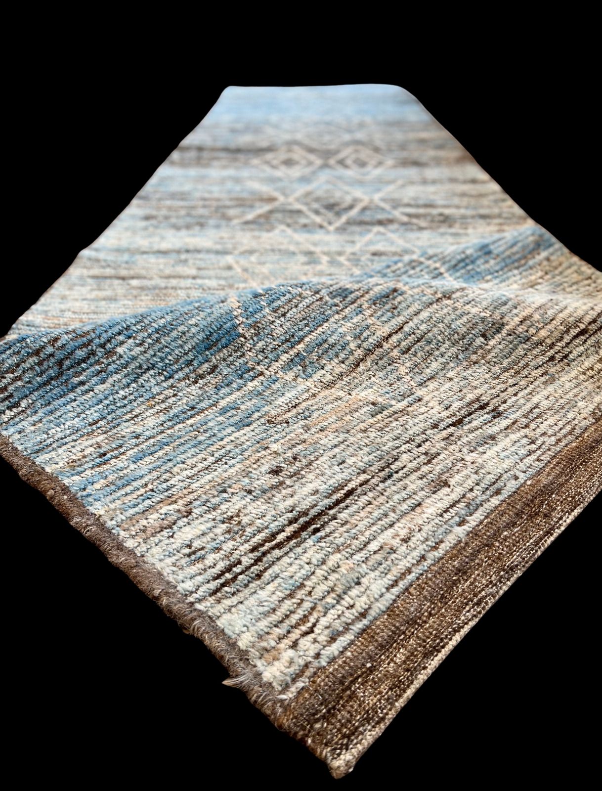 A long blue and brown rug is sitting on a black surface.