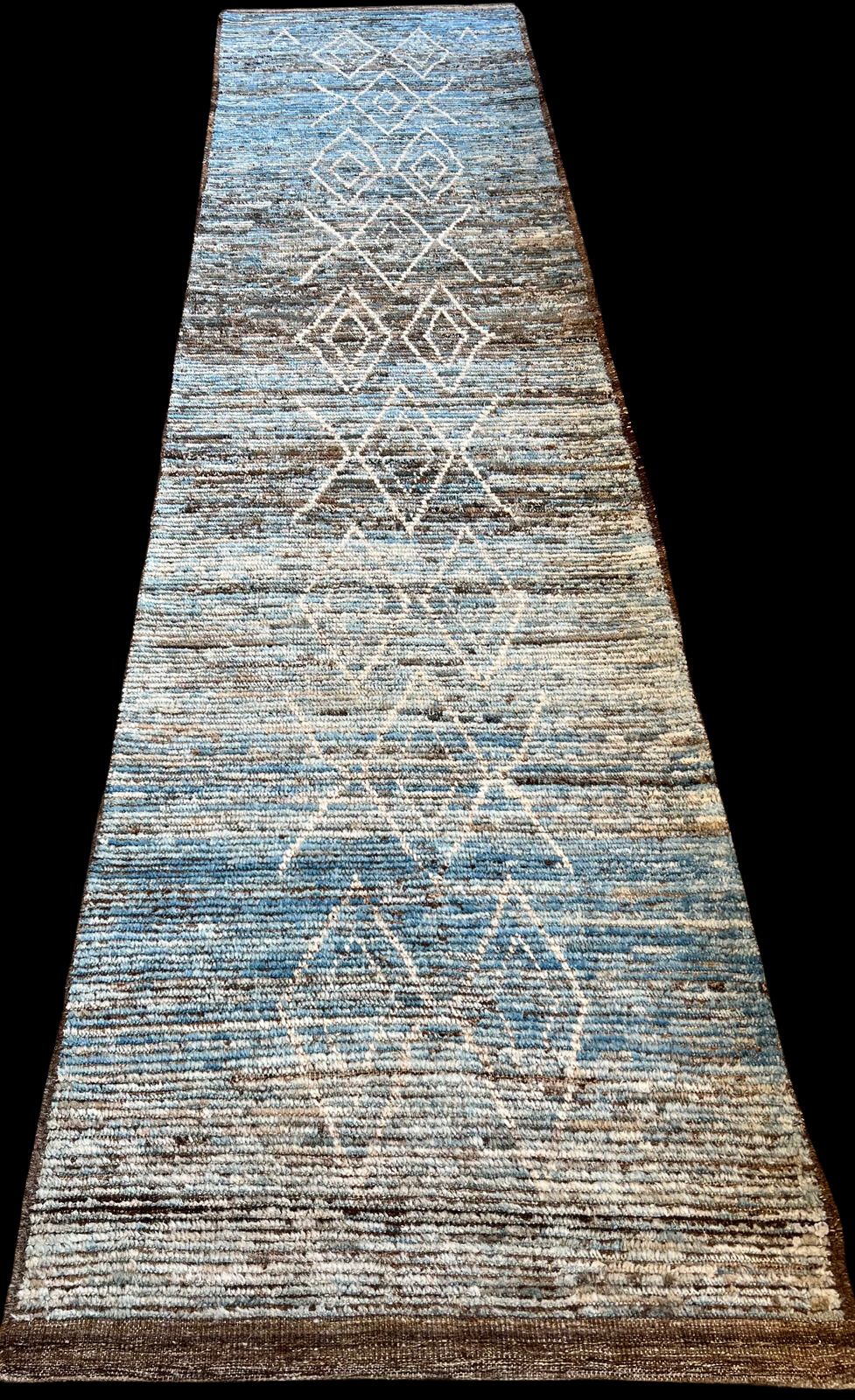 A long blue and brown rug is sitting on a black surface.