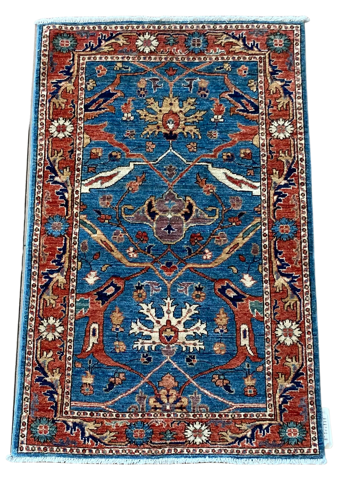 A blue and red rug with a floral pattern on a white background.