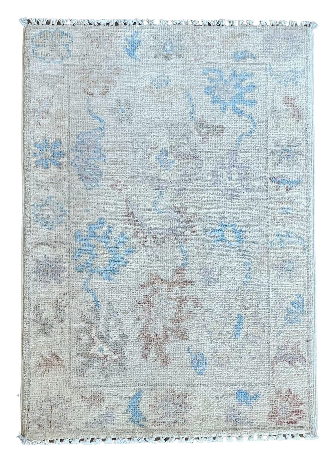 A rug with a floral pattern and fringe on a white background.