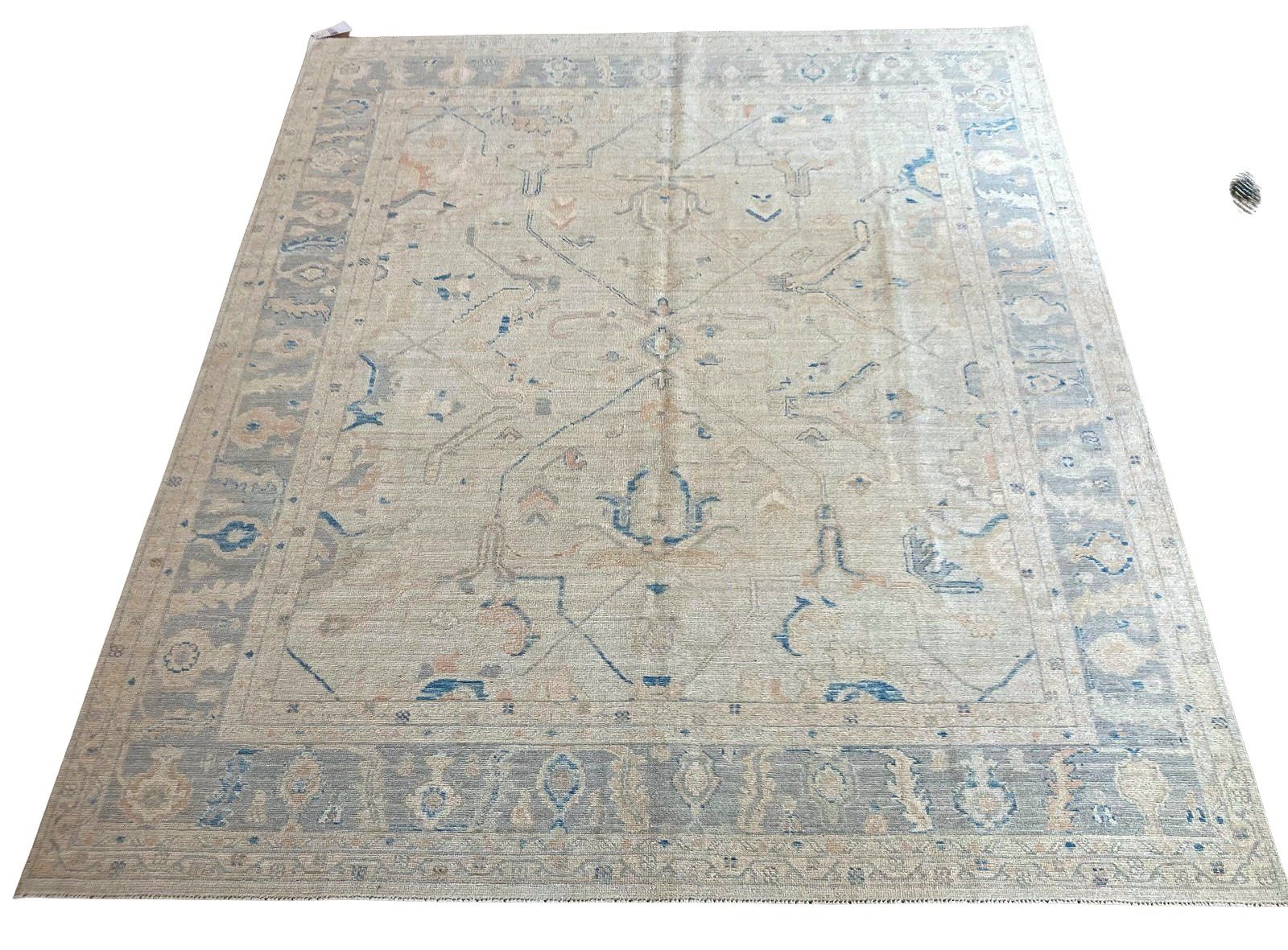 A rug with a blue border is sitting on a white surface.