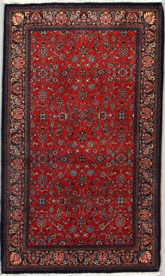 A red rug with a black border is sitting on a white surface.