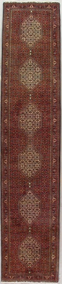 A red rug with a pattern on it is sitting on a white surface.