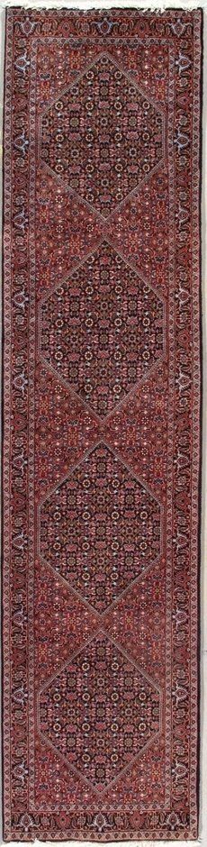 A red rug with a pattern on it is sitting on a white surface.