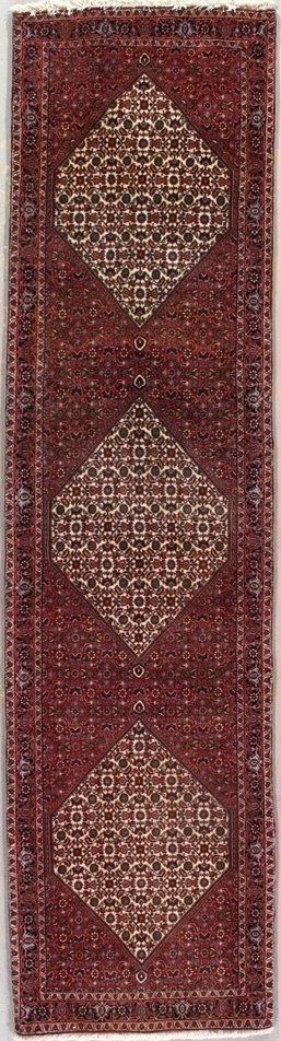 A red rug with diamonds on it is hanging on a wall.