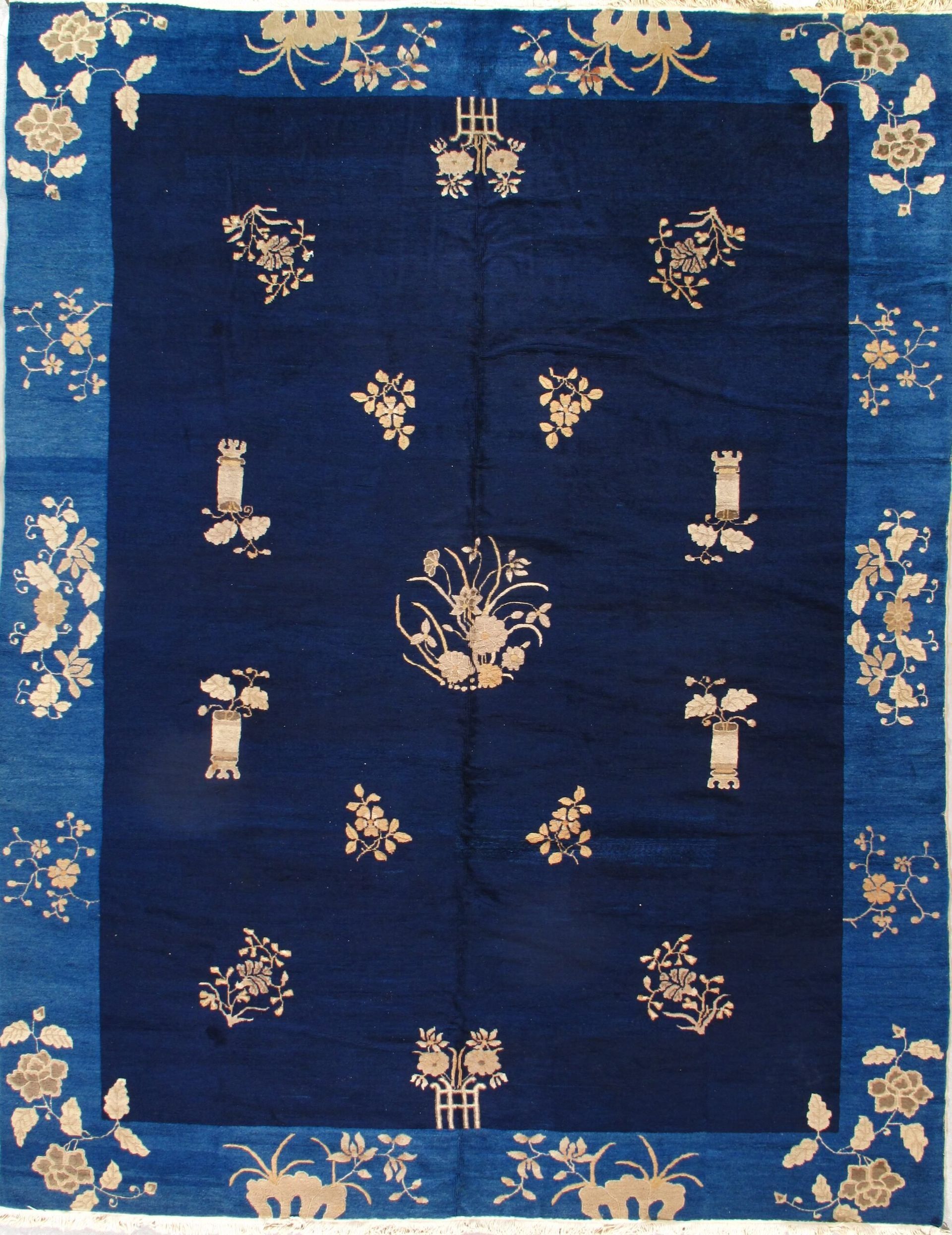 A blue rug with flowers and vases on it