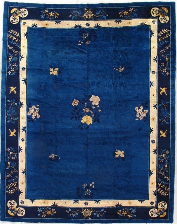 A blue rug with a white border and flowers on it