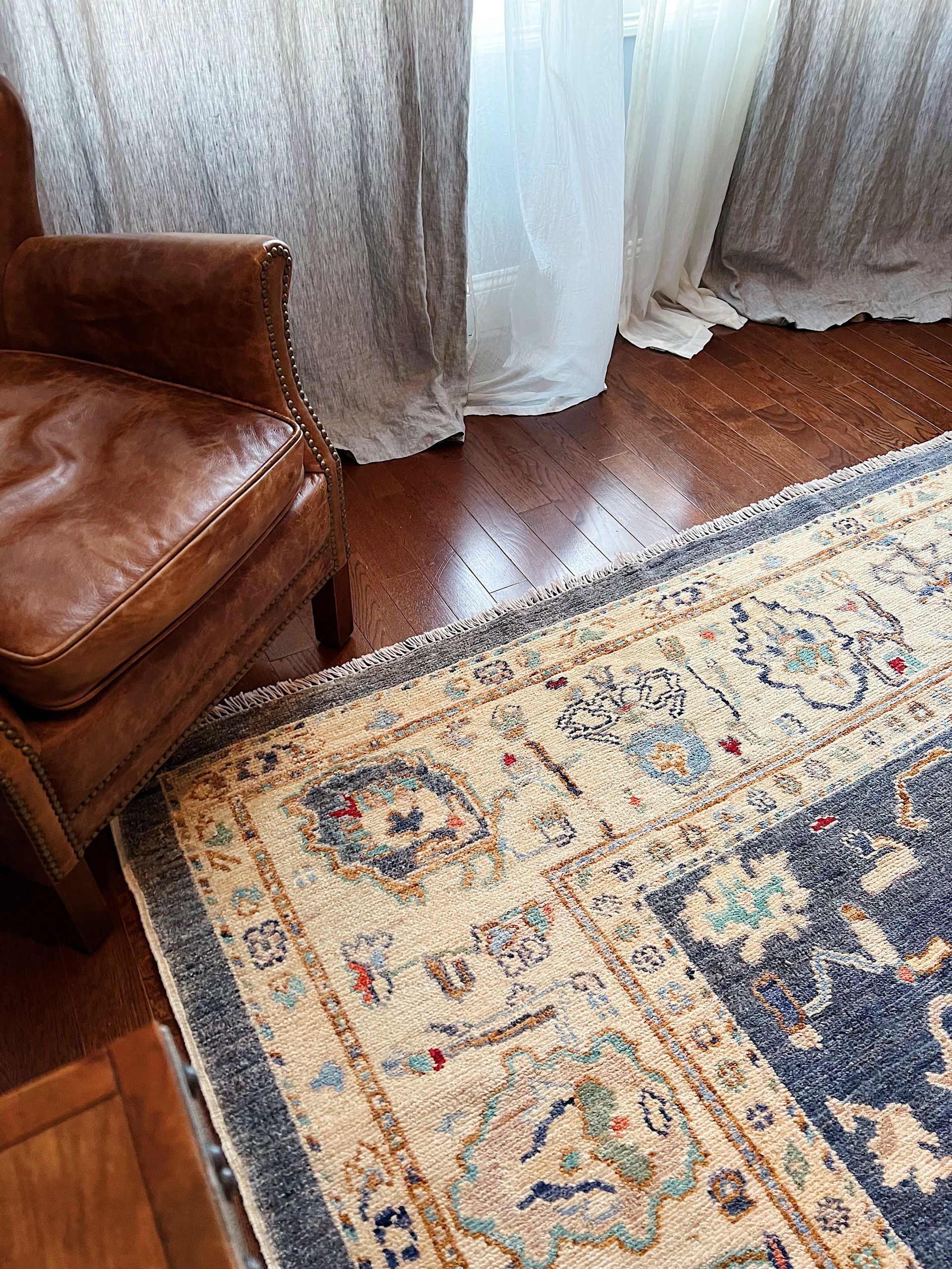 A leather chair is sitting next to a rug in a living room.