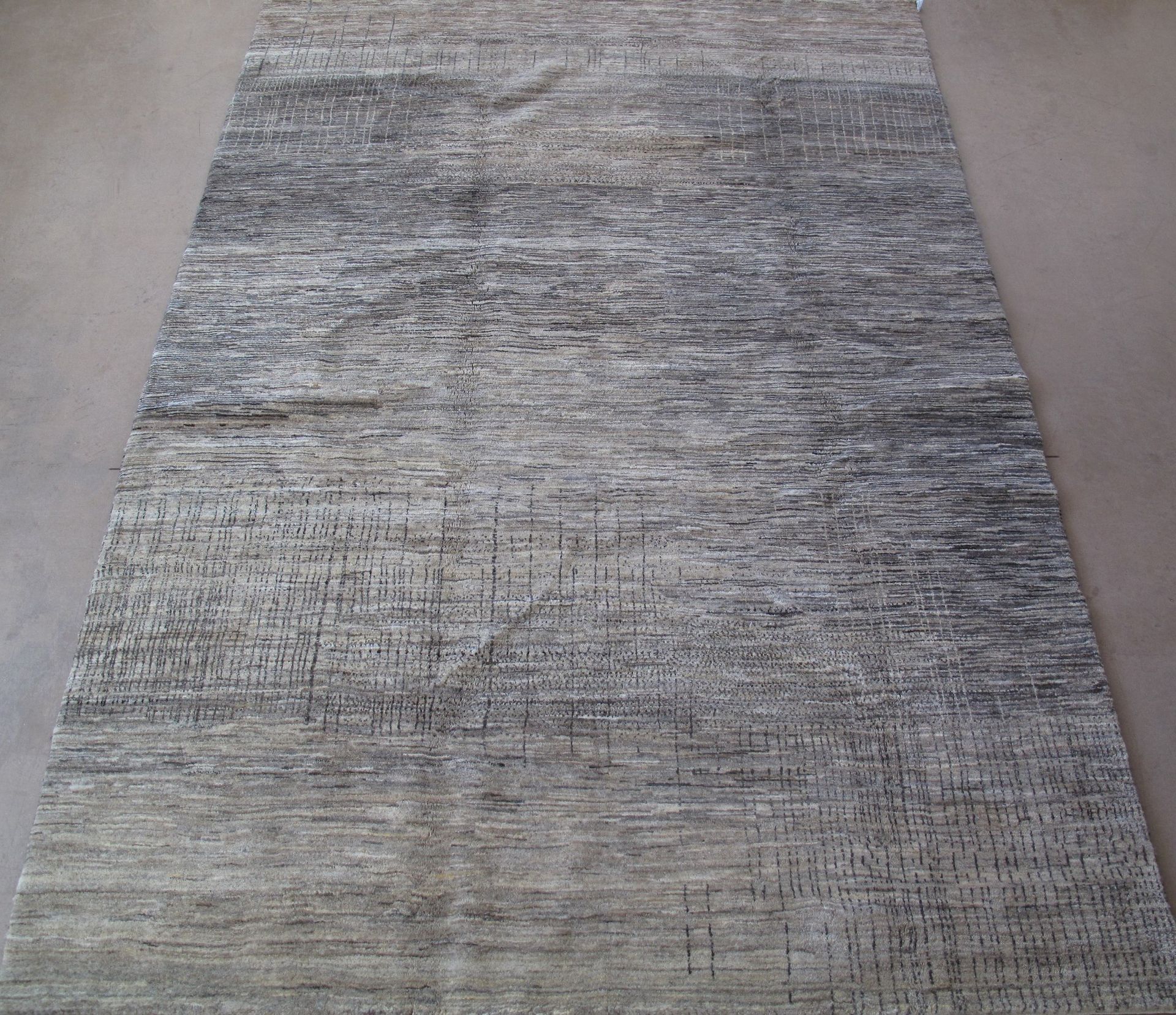 A gray rug is sitting on a concrete floor.