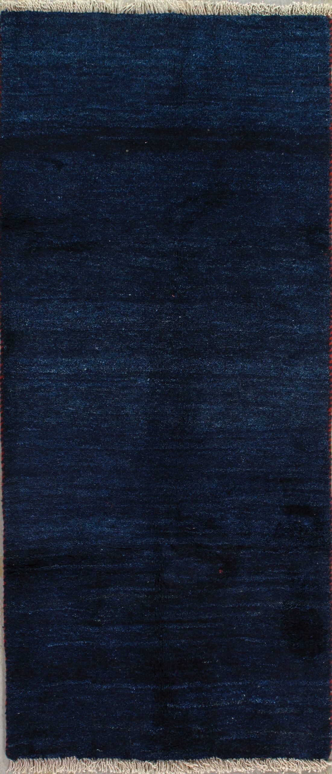 A blue rug with fringe is sitting on a table.
