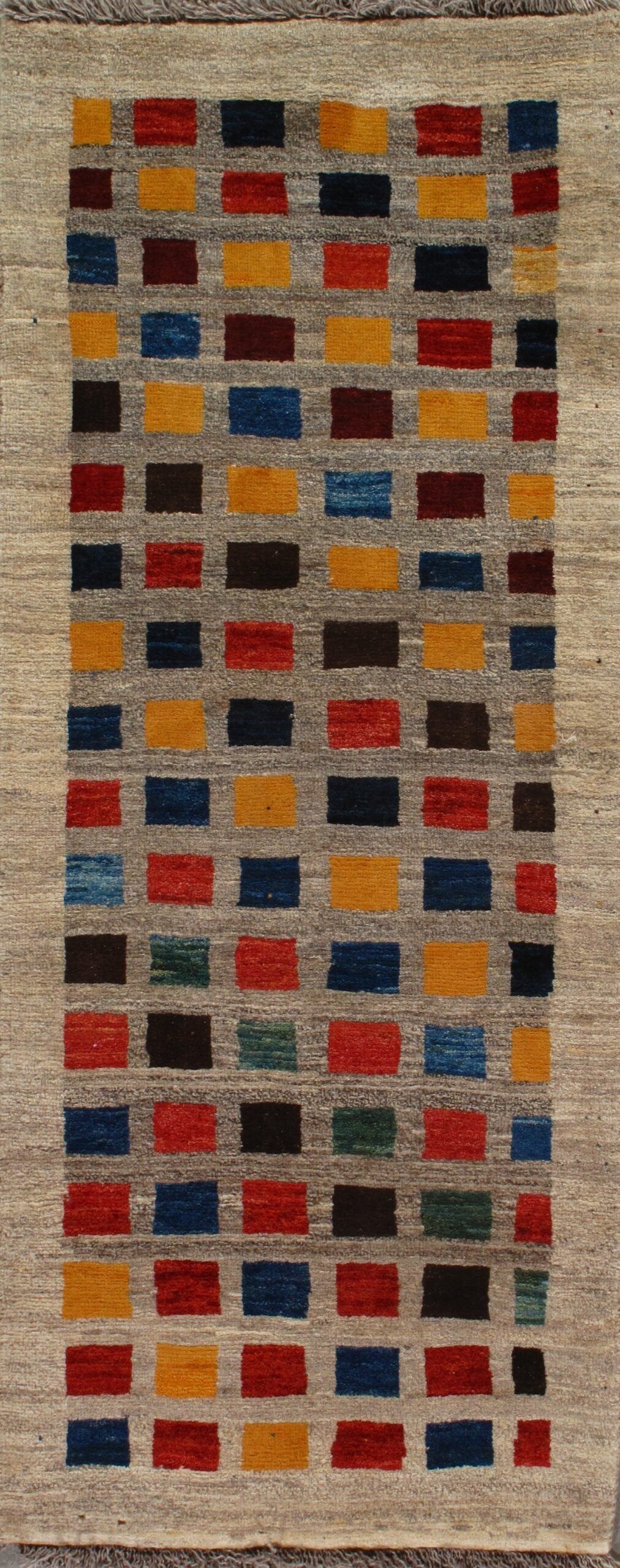 A rug with a colorful pattern on it is hanging on a wall.