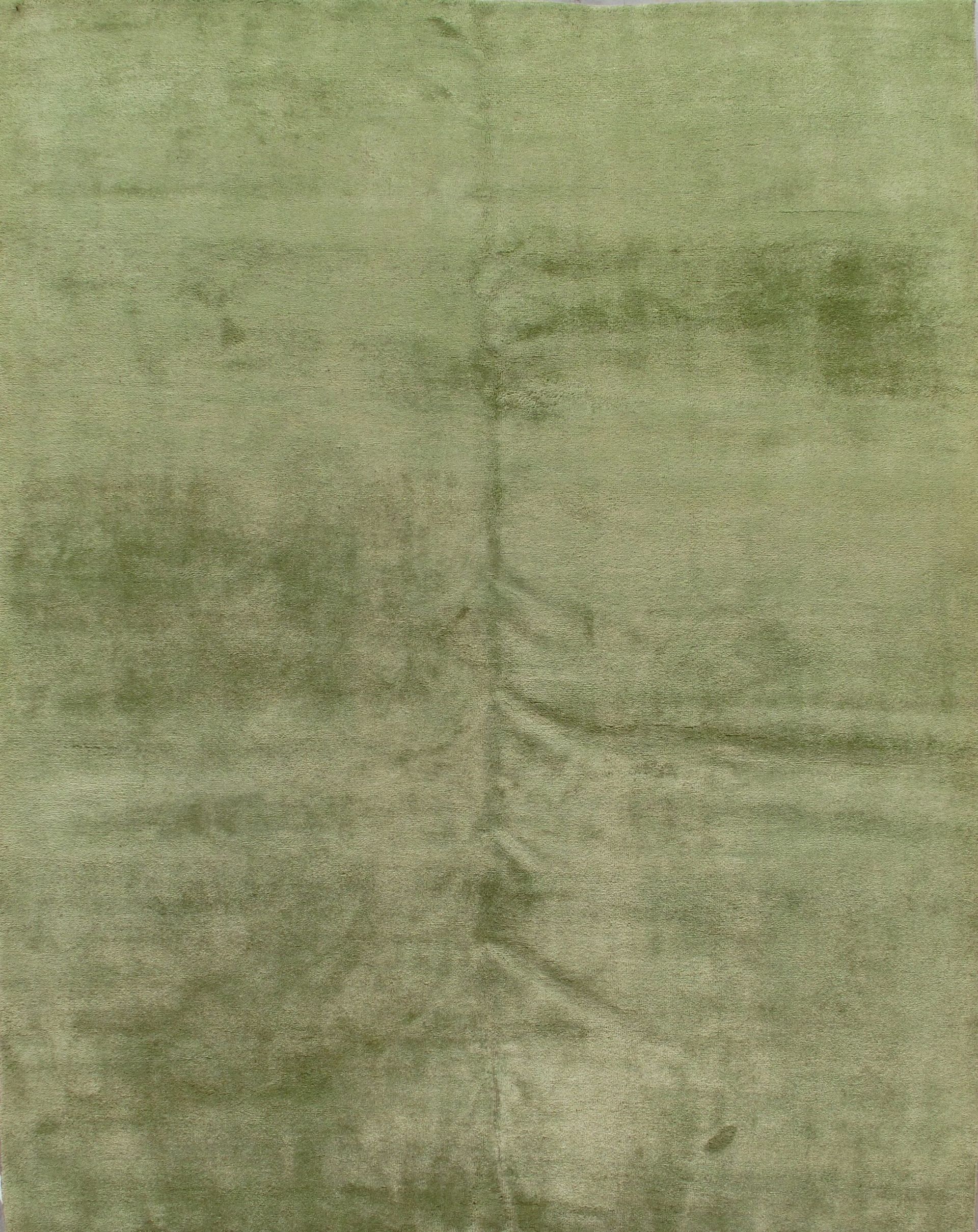 A close up of a green rug on a white surface.