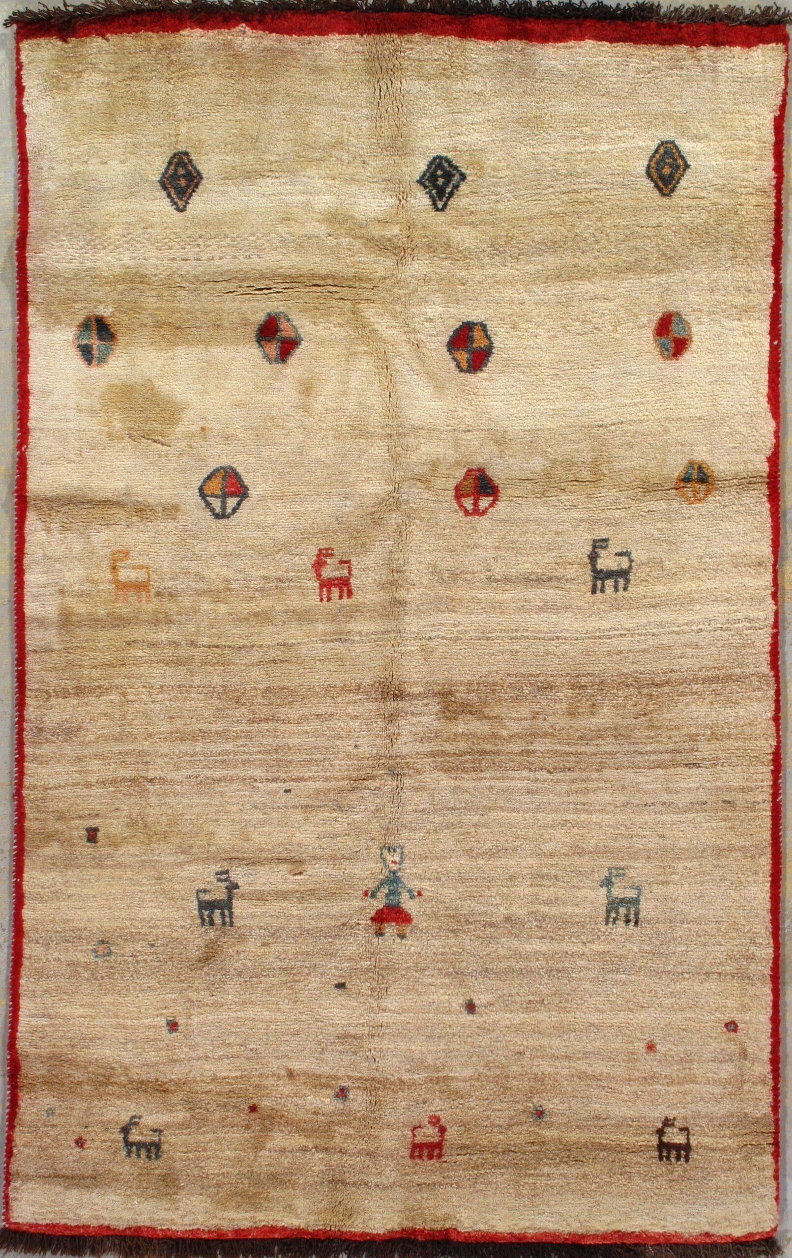 A rug with a red border is hanging on a wall.