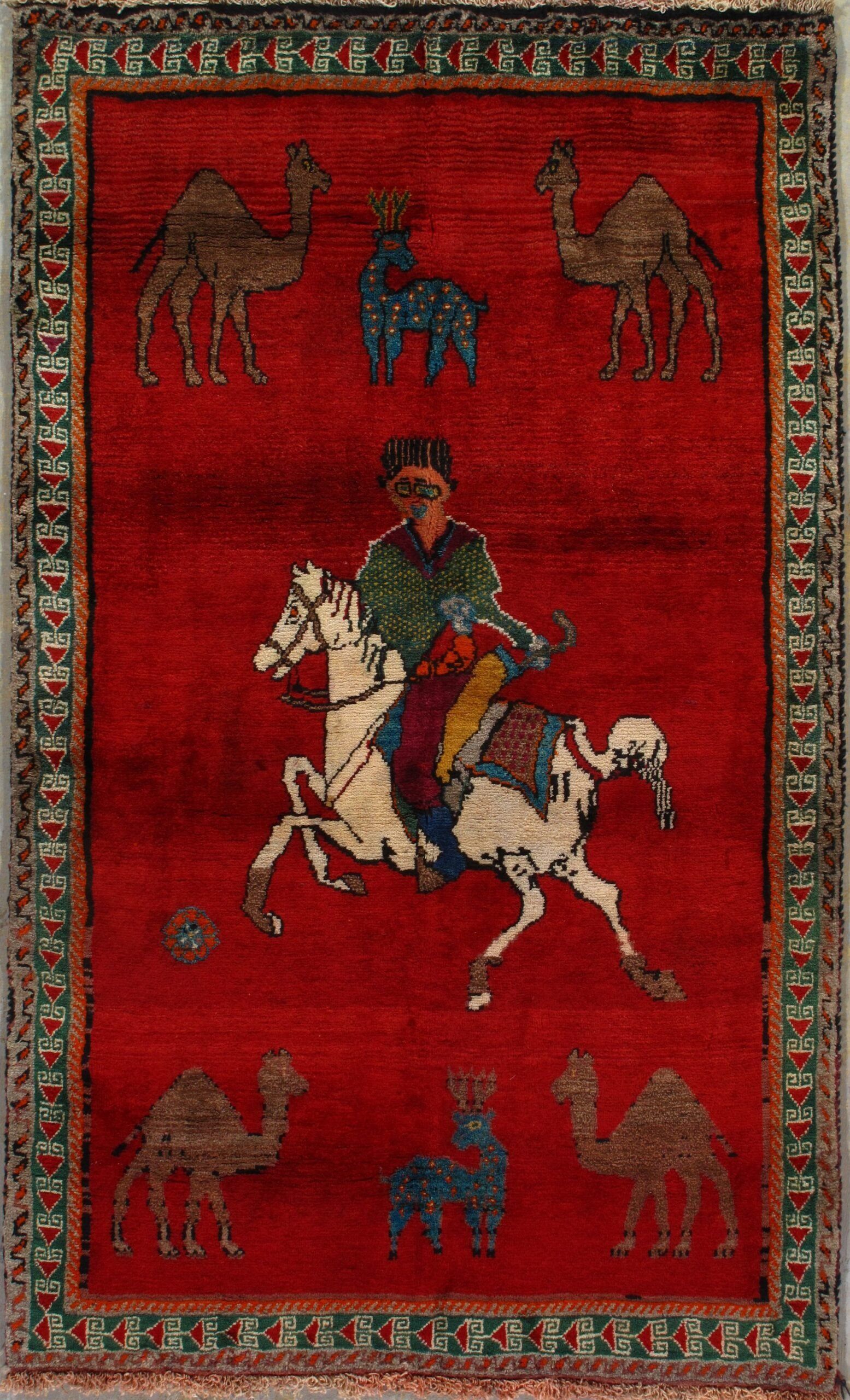 A rug with a man riding a horse and camels on it.