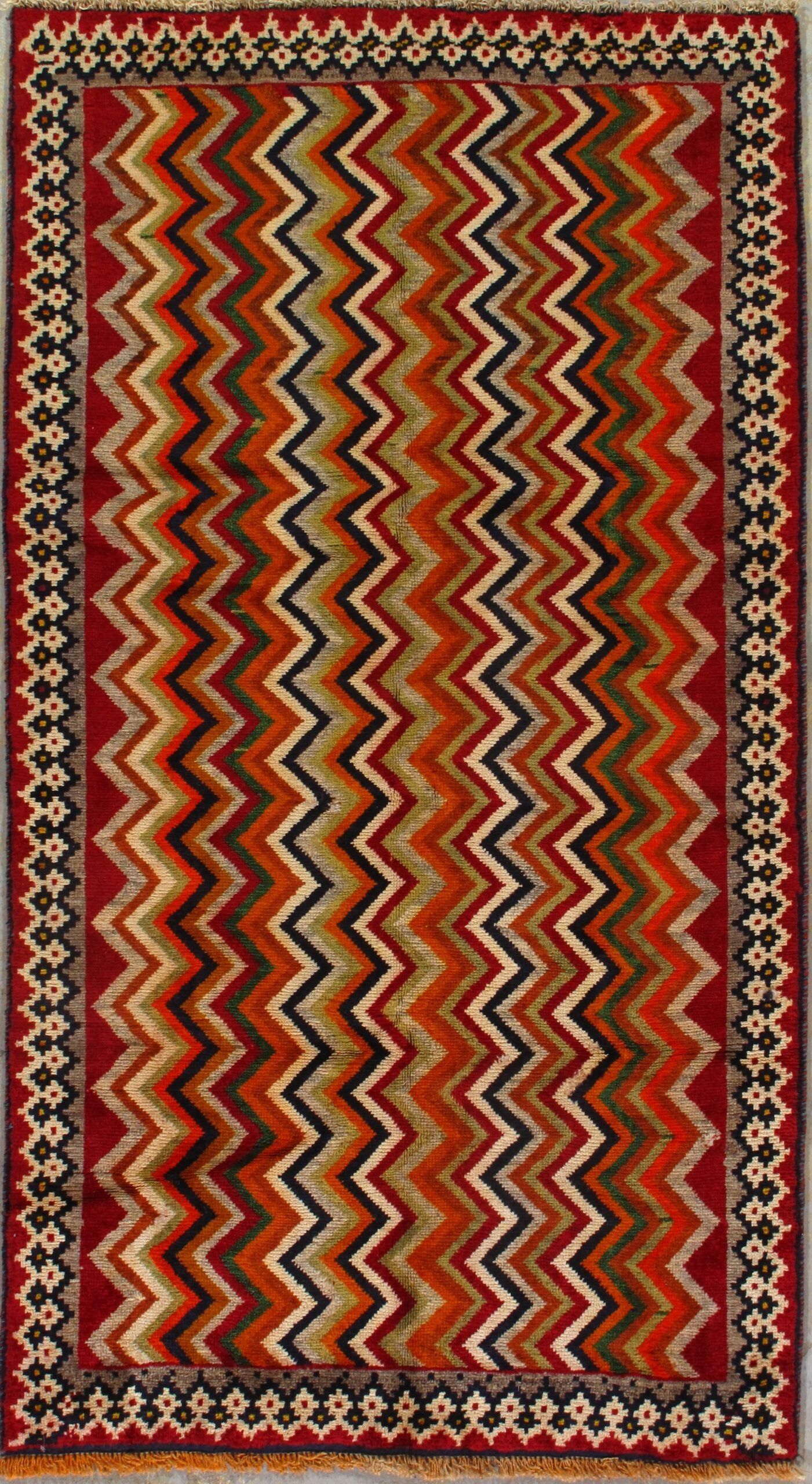 A colorful rug with a zigzag pattern and a red border