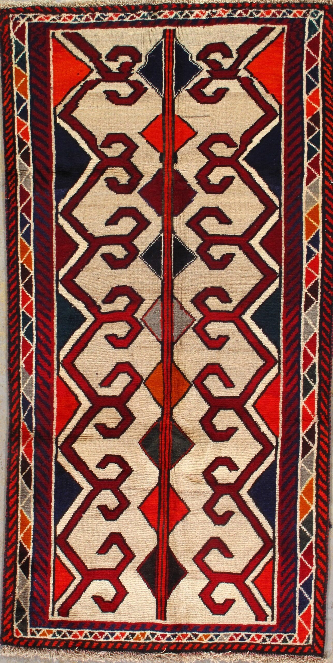 A rug with a geometric pattern on it is hanging on a wall.